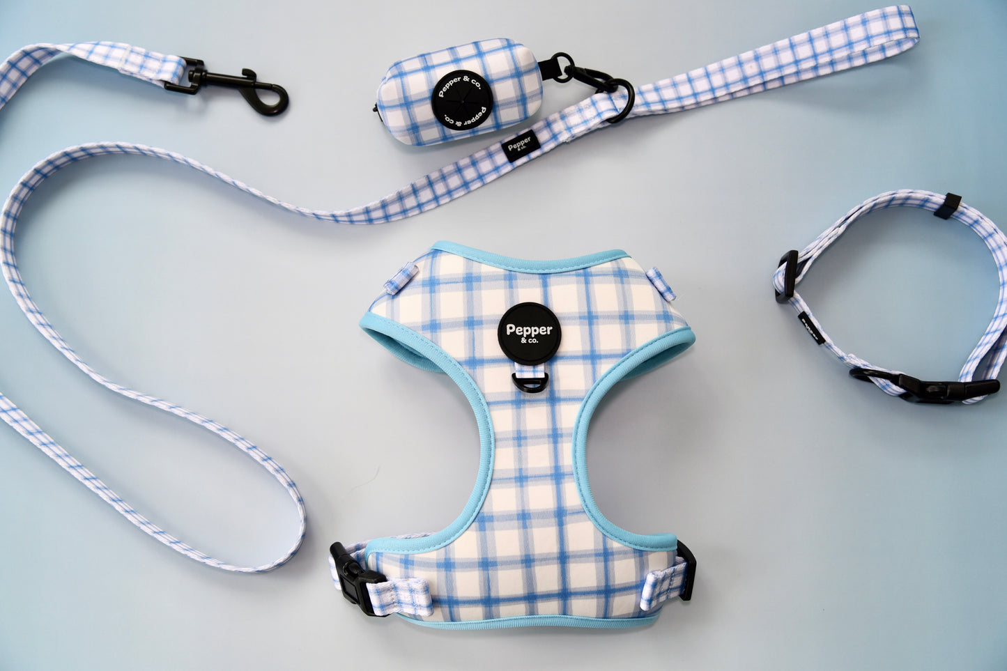 Dog harness, leash, and collar set with blue and white plaid pattern on gray background.