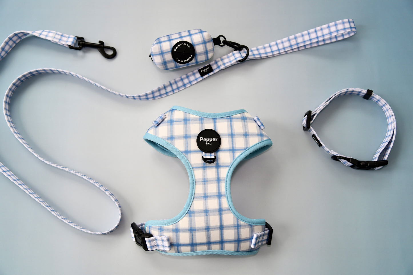Pet harness, leash, and collar set with plaid pattern on gray background