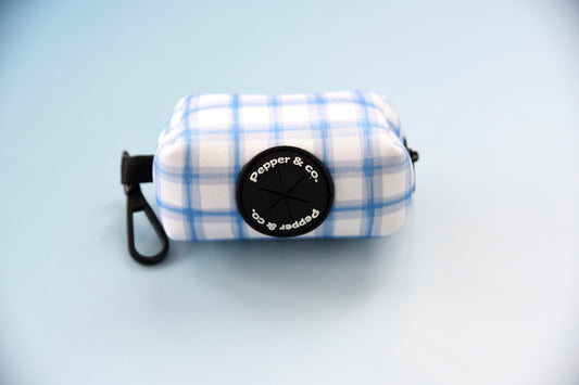 A plaid-patterned baby blue and white pet waste bag holder with a black clip