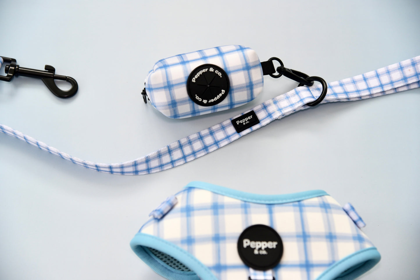 Pet accessories with blue and white plaid pattern on a light gray background.