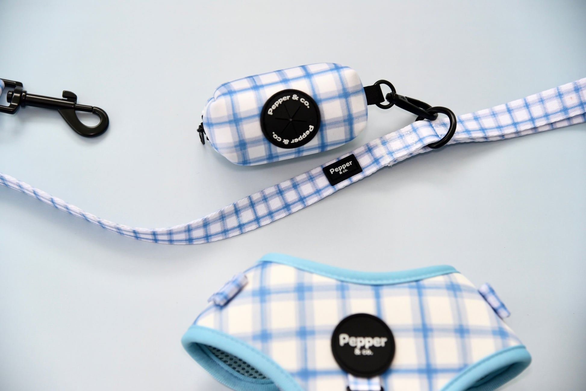 Pet accessories with blue and white plaid pattern on a light gray background.