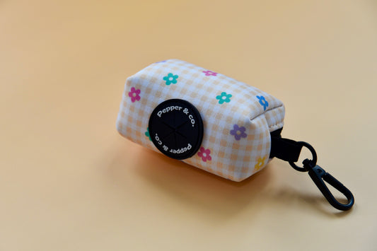 Small pouch with floral pattern and black clip on a beige background