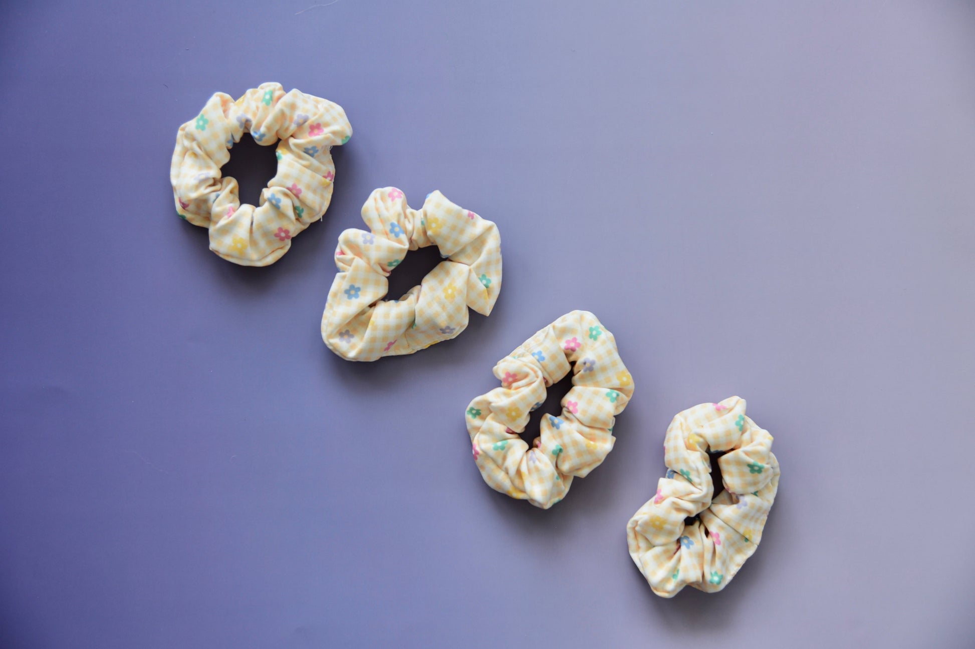 Four colorful scrunchies on a purple background