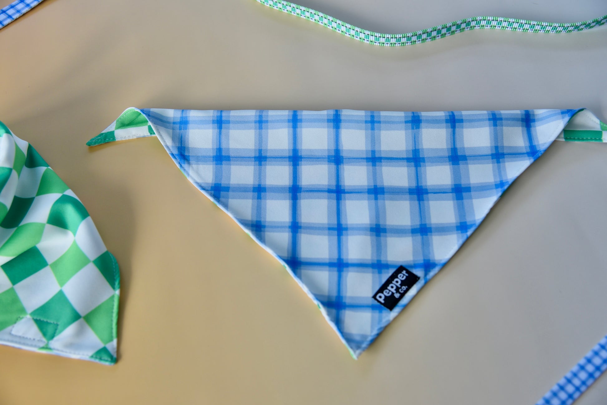 Two dog bandanas with different patterns on a beige surface