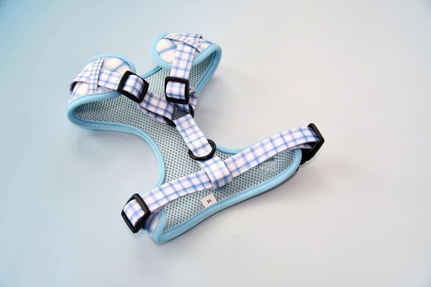 Blue and white checkered pet harness on a light blue background