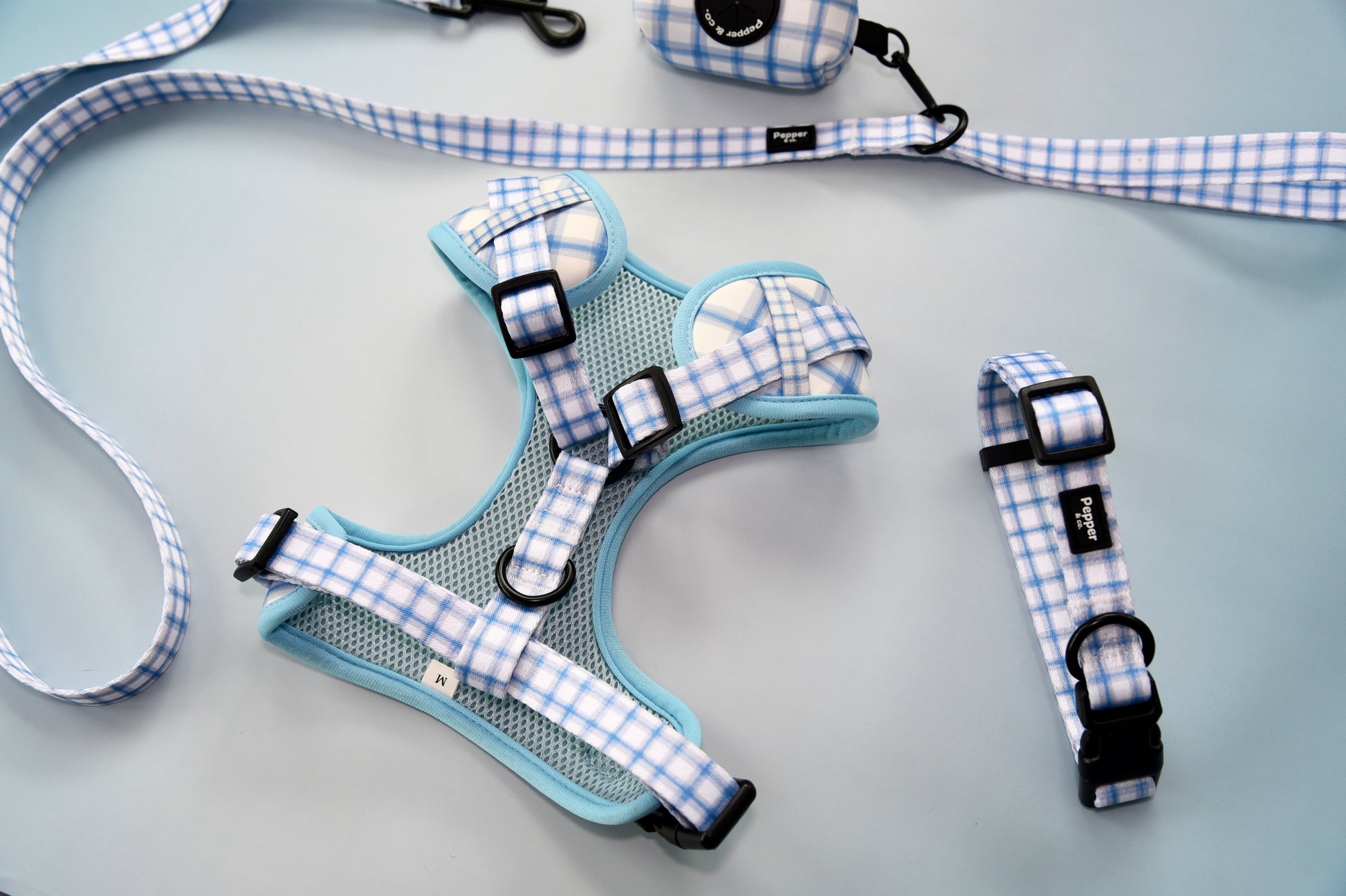 Dog harness and collar set with blue and white checkered pattern on a light background.
