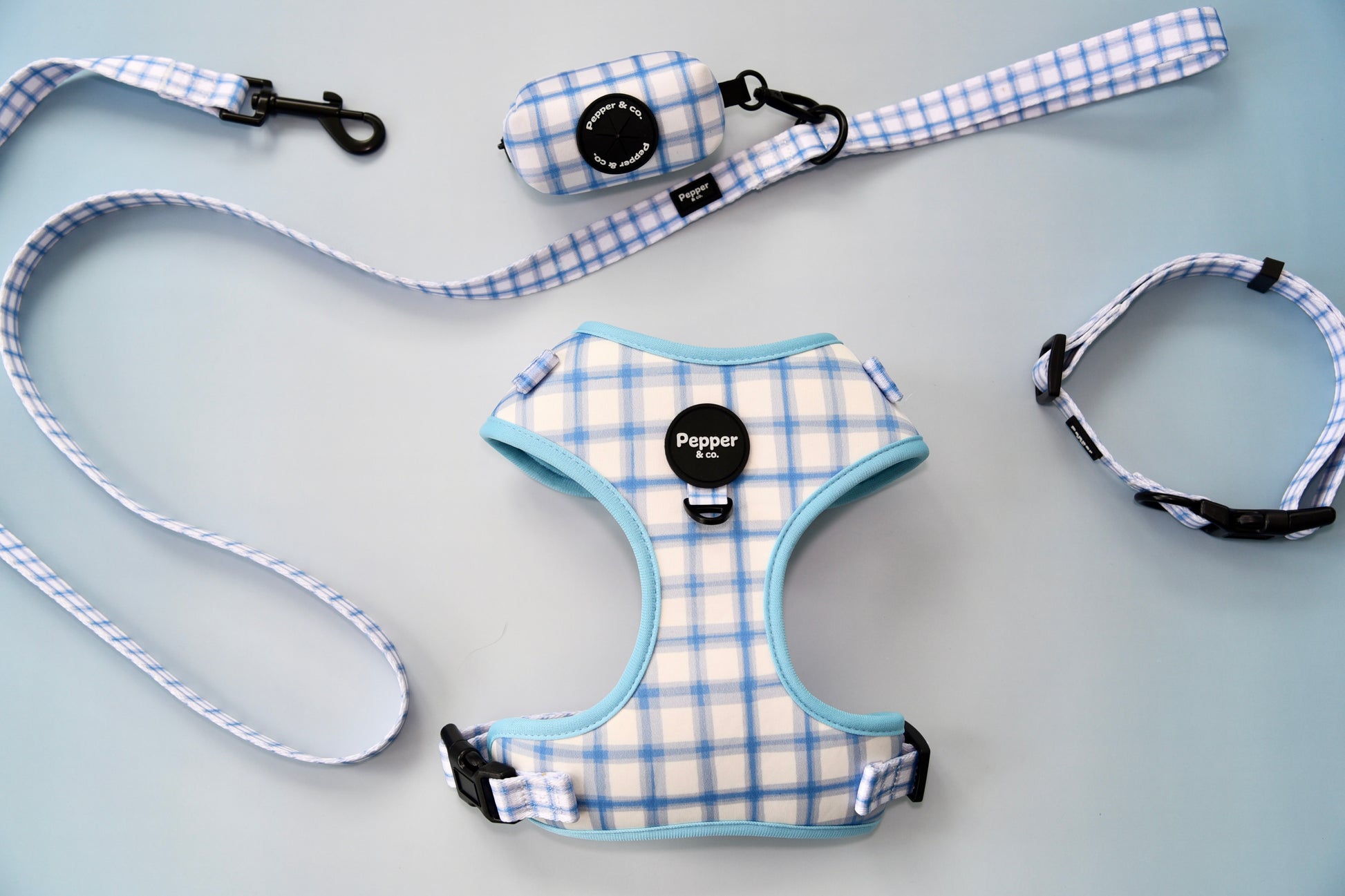 Dog harness, leash, and collar set with blue and white plaid pattern on gray background.