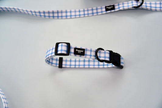 Dog collar with blue and white checkered pattern on a light gray background.