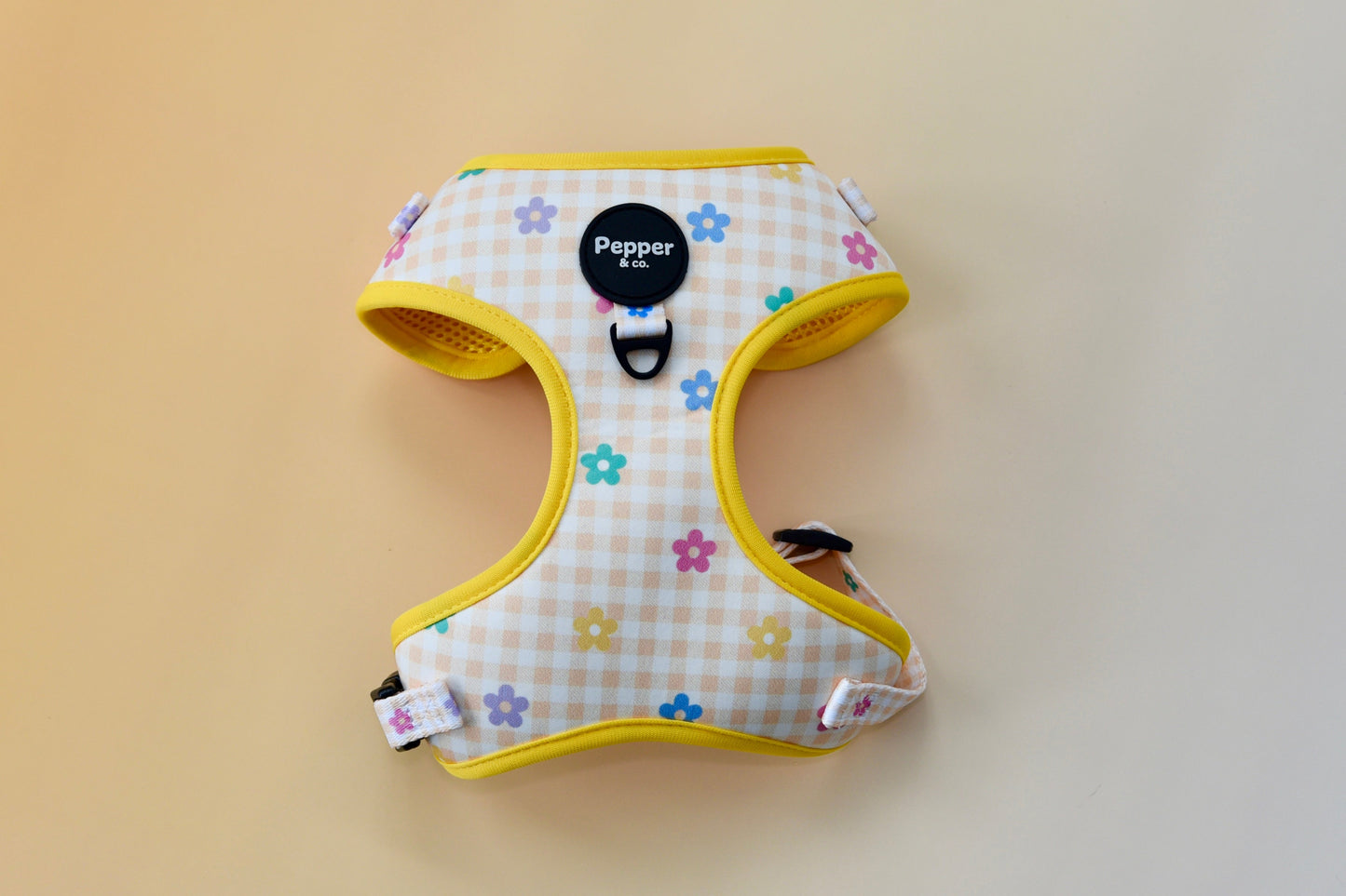 Dog harness with floral pattern and yellow trim on a plain background
