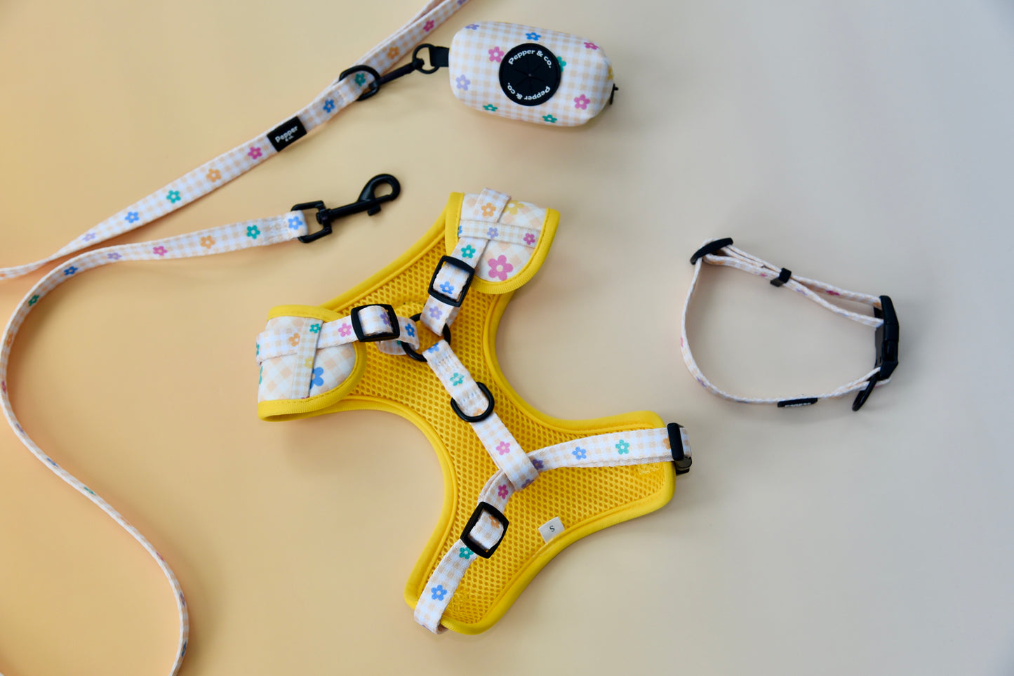 Yellow dog harness with floral patterned straps on a beige background