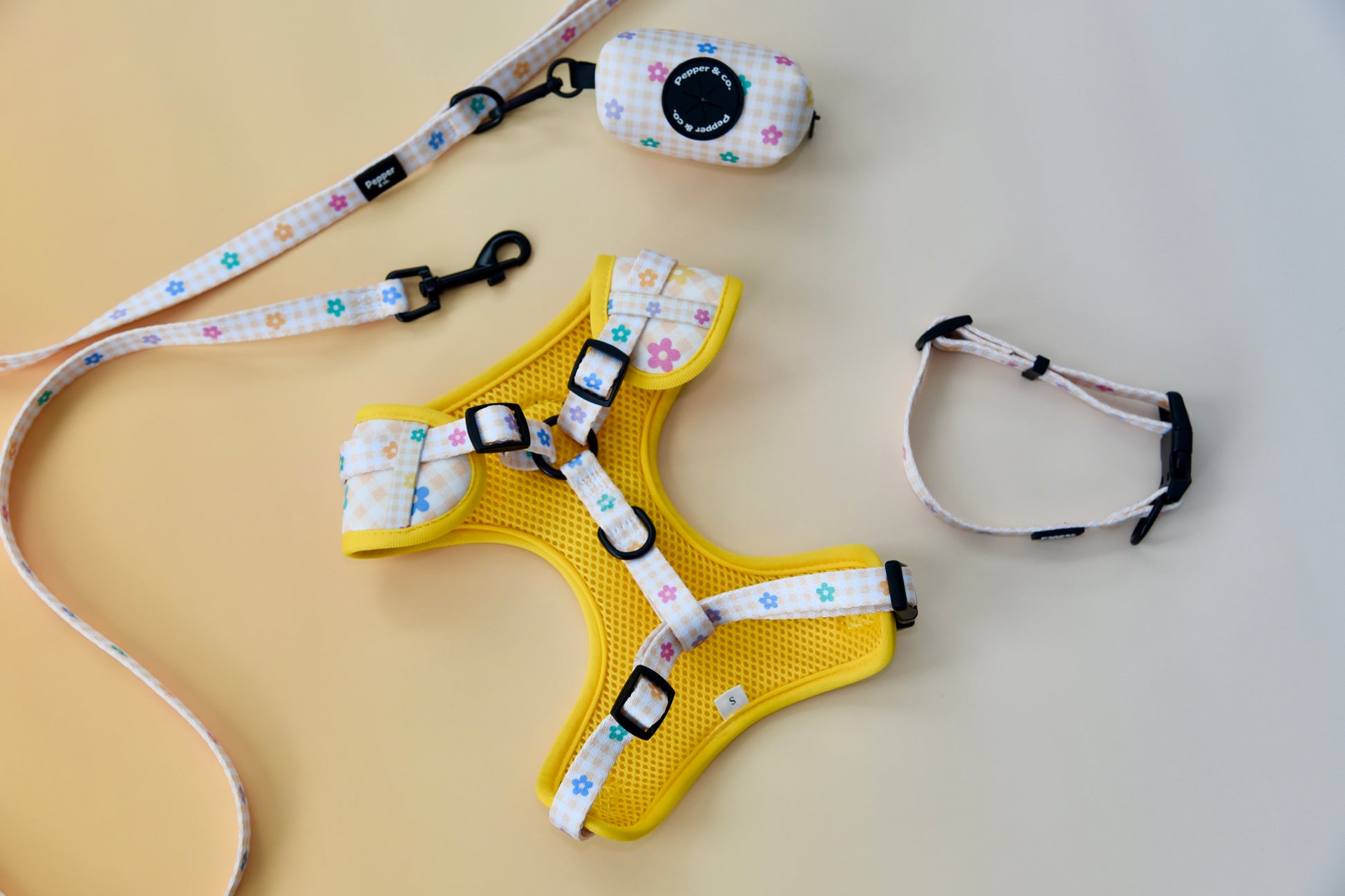 Yellow dog harness with floral patterned straps on a beige background