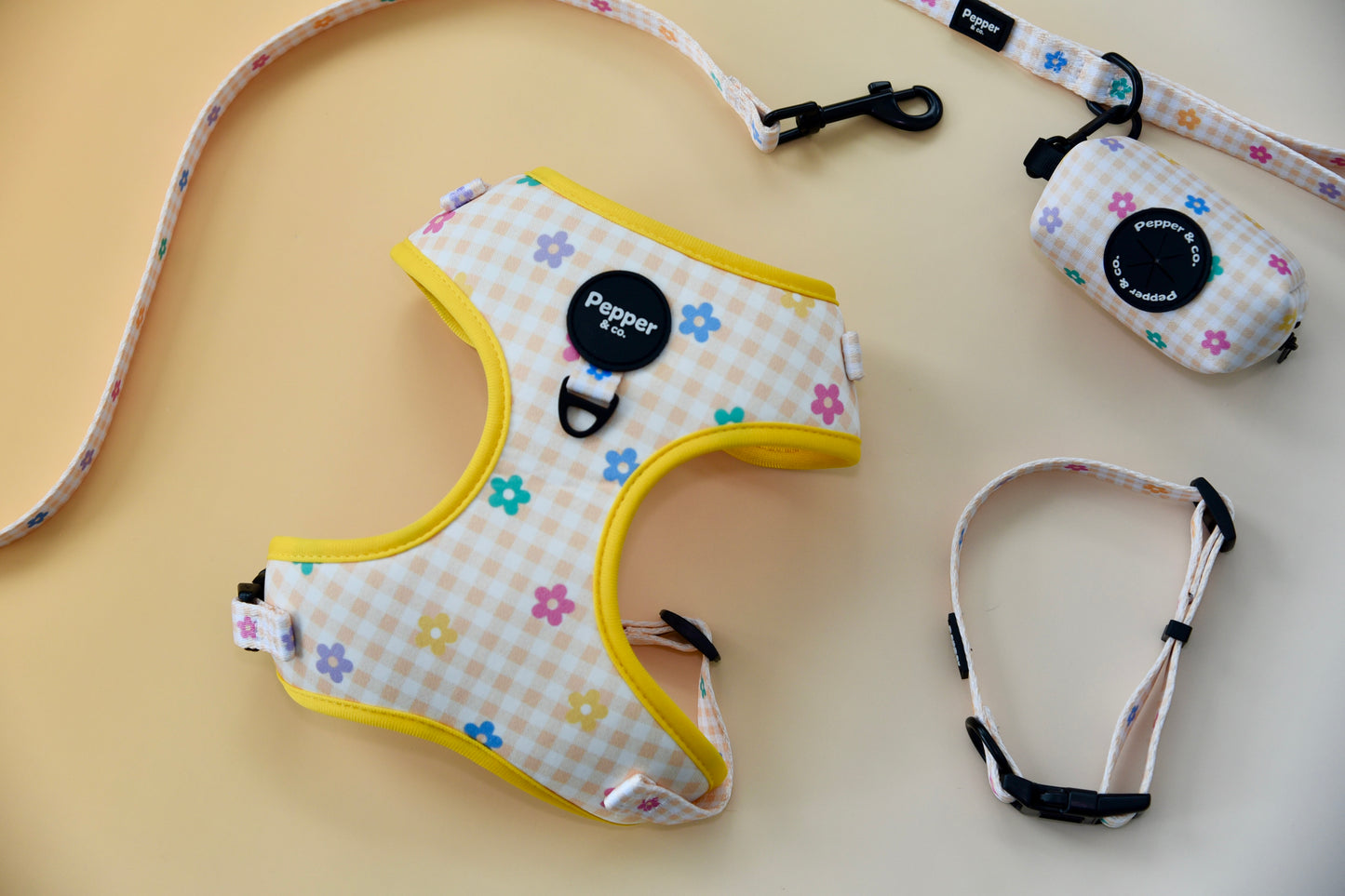 Dog harness with floral pattern and colorful leash on a beige background