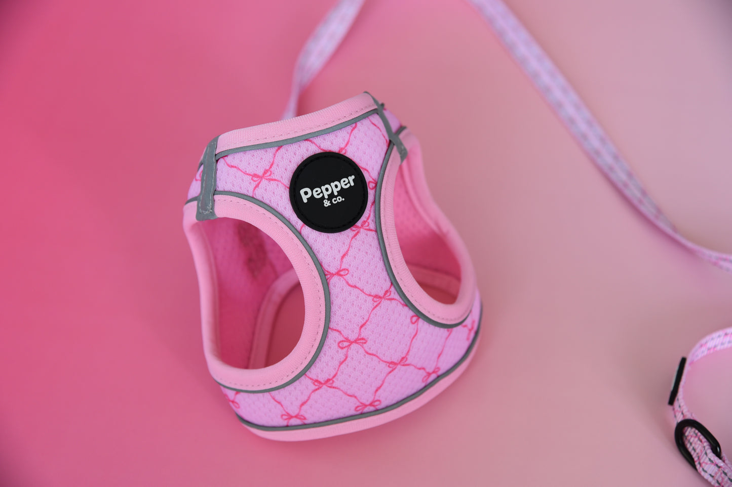 Pink dog harness with 'Pepper' label on a pink background